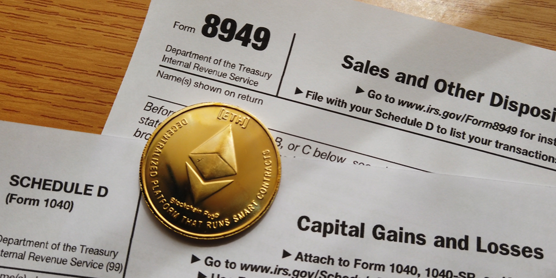 A gold ethereum crypto coin sits atop capital gains tax forms